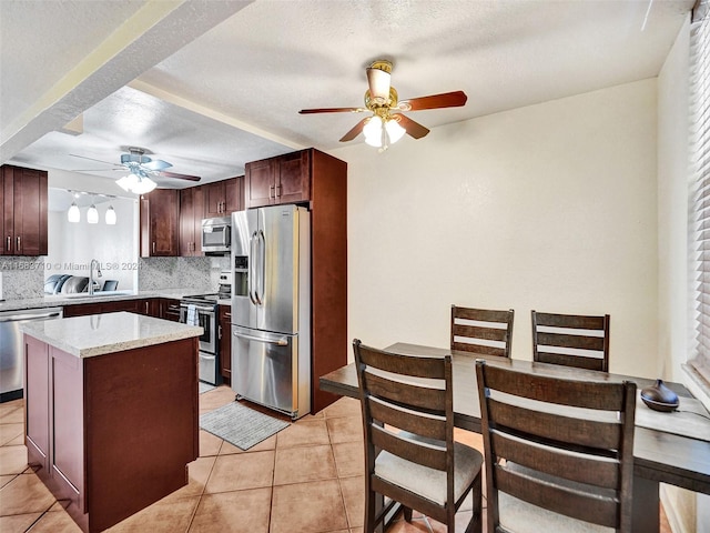 kitchen with decorative backsplash, a kitchen island, appliances with stainless steel finishes, a textured ceiling, and sink