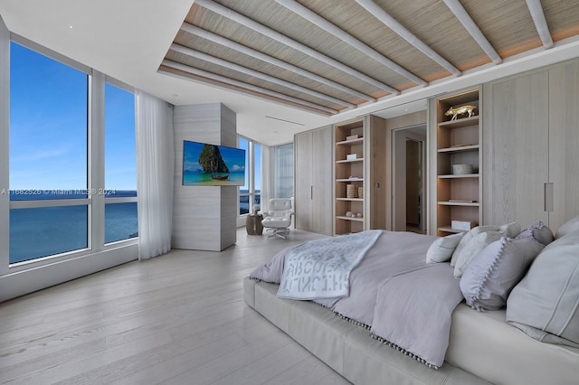 bedroom with floor to ceiling windows, multiple windows, and light wood-type flooring