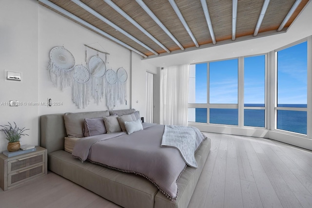 bedroom with light hardwood / wood-style floors and a water view