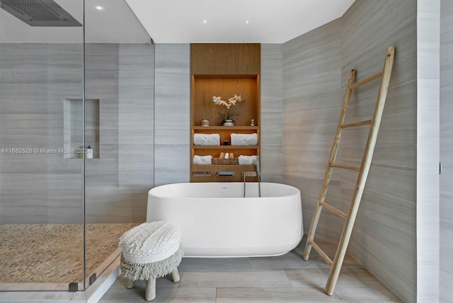 bathroom with tile patterned flooring, tile walls, and shower with separate bathtub