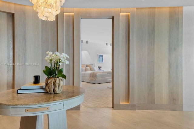 hallway with a notable chandelier and light hardwood / wood-style floors