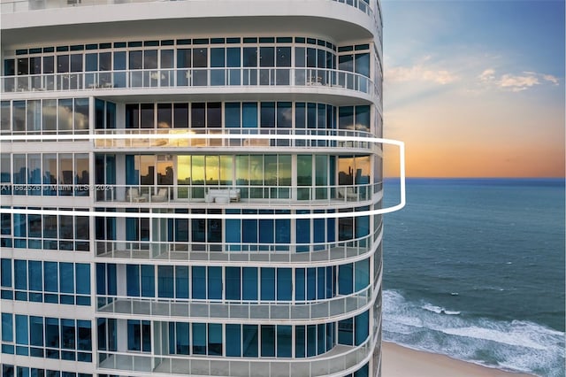 outdoor building at dusk featuring a view of the beach and a water view