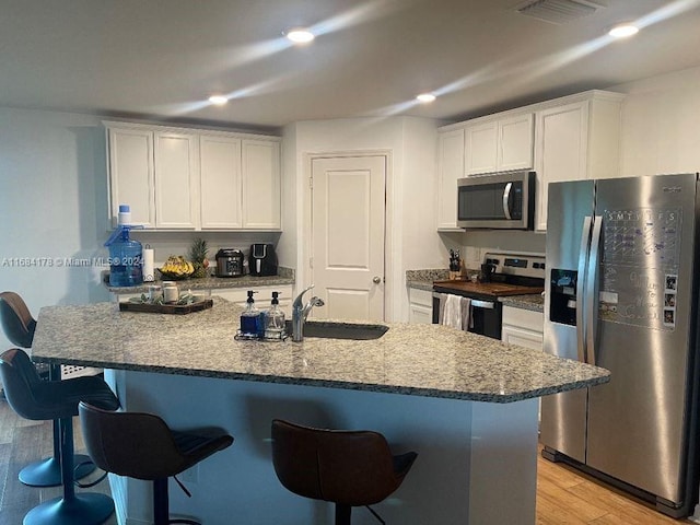 kitchen featuring appliances with stainless steel finishes, a breakfast bar, light wood-type flooring, and white cabinets