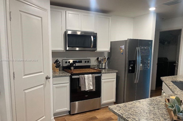 kitchen featuring light hardwood / wood-style floors, white cabinetry, stainless steel appliances, and light stone counters