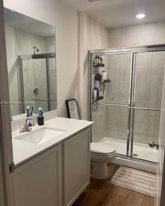 bathroom with vanity, toilet, wood-type flooring, and a shower with door