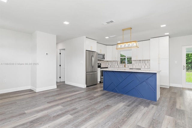 kitchen featuring stainless steel appliances, backsplash, a kitchen island, pendant lighting, and white cabinets