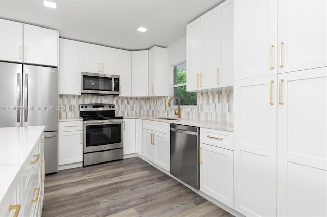 kitchen with white cabinets, appliances with stainless steel finishes, sink, and light stone counters