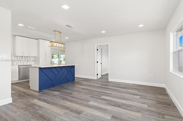 kitchen featuring tasteful backsplash, dishwasher, hardwood / wood-style flooring, hanging light fixtures, and white cabinets