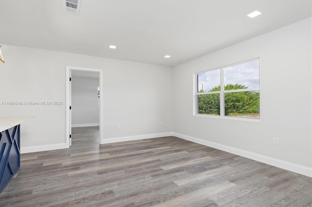 empty room with recessed lighting, wood finished floors, visible vents, and baseboards