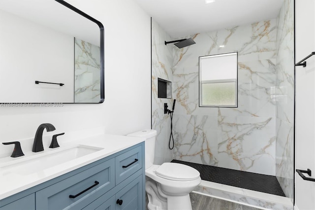 bathroom with toilet, vanity, hardwood / wood-style floors, and a tile shower