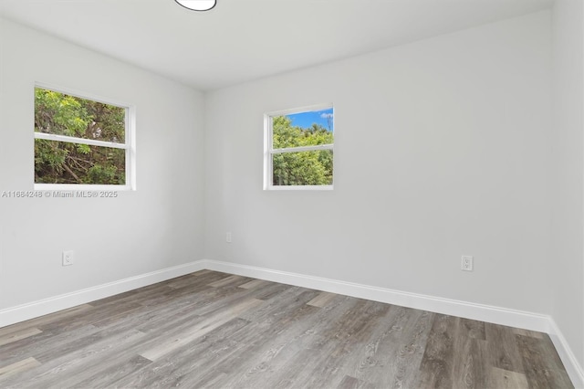 unfurnished room with a healthy amount of sunlight, baseboards, and wood finished floors