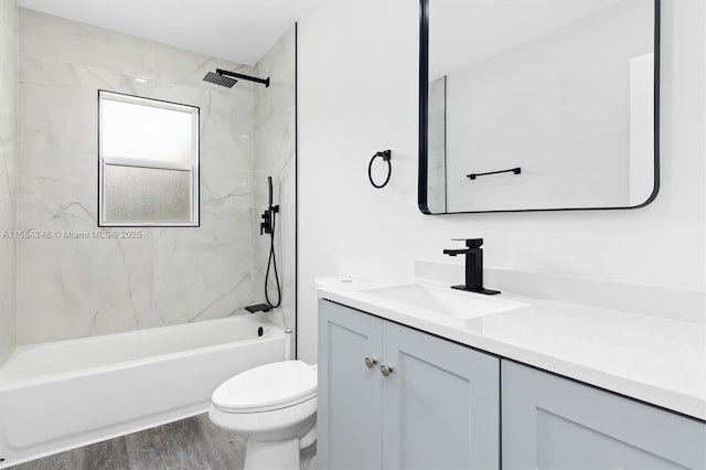 full bathroom with toilet, tiled shower / bath, hardwood / wood-style floors, and vanity