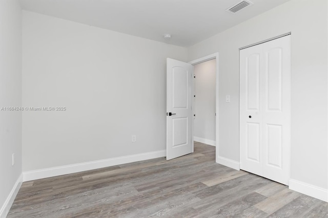 unfurnished bedroom with light wood-type flooring and a closet