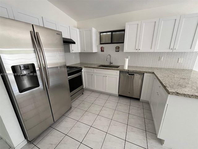 kitchen with light stone counters, stainless steel appliances, vaulted ceiling, sink, and white cabinets