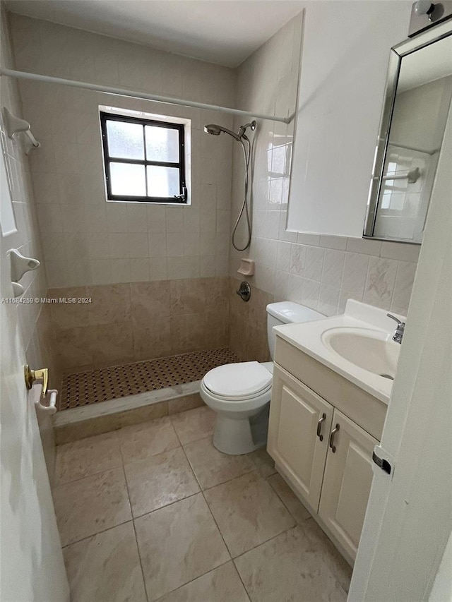 bathroom with tasteful backsplash, vanity, tiled shower, tile walls, and toilet