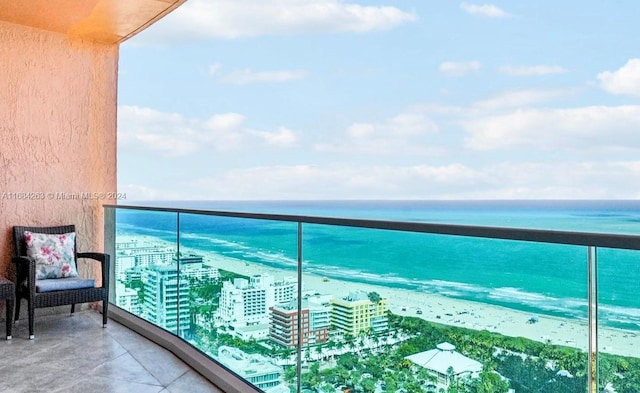 balcony with a water view and a view of the beach