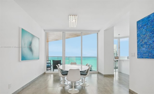 dining space with a water view, concrete flooring, a wall of windows, and a wealth of natural light