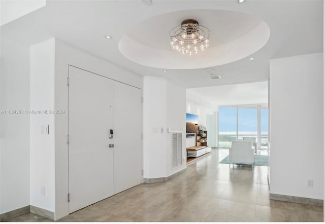 foyer entrance with a raised ceiling and floor to ceiling windows