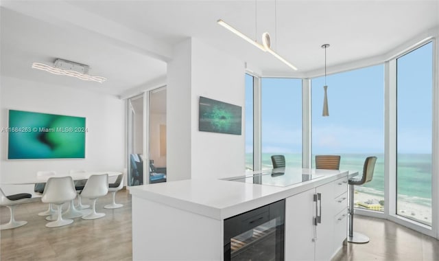 kitchen featuring white cabinets, pendant lighting, a water view, and a wealth of natural light