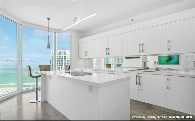 kitchen featuring white cabinets, black electric stovetop, a center island, and hanging light fixtures