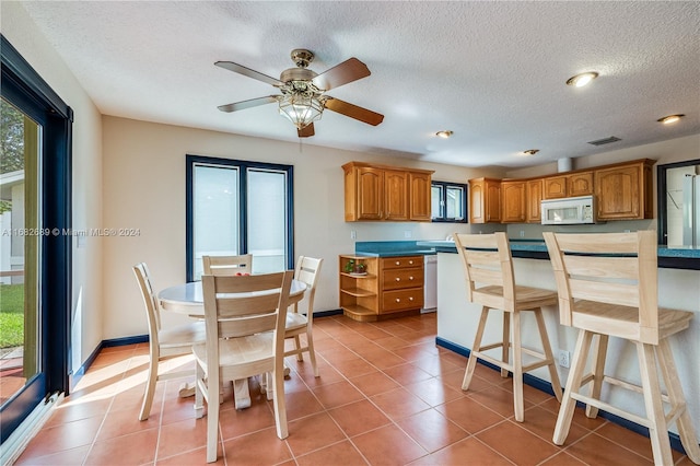 kitchen featuring a kitchen breakfast bar, a textured ceiling, tile patterned floors, and ceiling fan