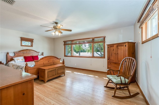 bedroom featuring light hardwood / wood-style floors, a textured ceiling, and ceiling fan