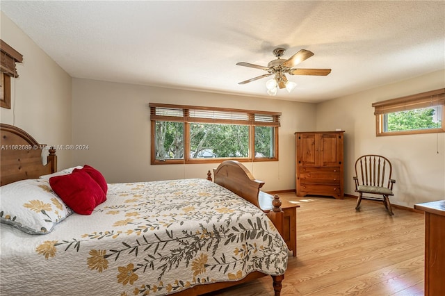 bedroom with light hardwood / wood-style flooring, a textured ceiling, and ceiling fan