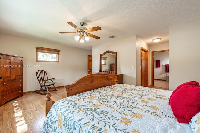 bedroom with light hardwood / wood-style floors, a textured ceiling, ensuite bath, and ceiling fan