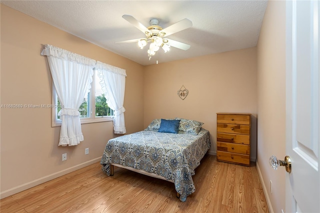 bedroom with a textured ceiling, light wood-type flooring, and ceiling fan