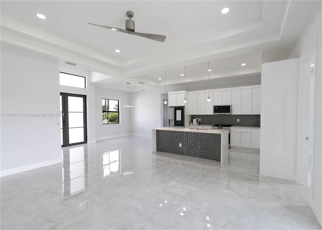 kitchen featuring decorative backsplash, an island with sink, hanging light fixtures, stainless steel appliances, and white cabinets