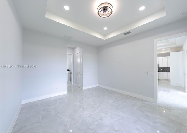 unfurnished room featuring a raised ceiling