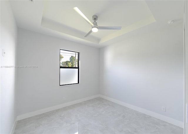 empty room featuring ceiling fan and a raised ceiling