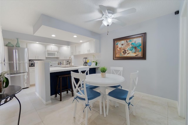 tiled dining room featuring ceiling fan, a textured ceiling, and sink