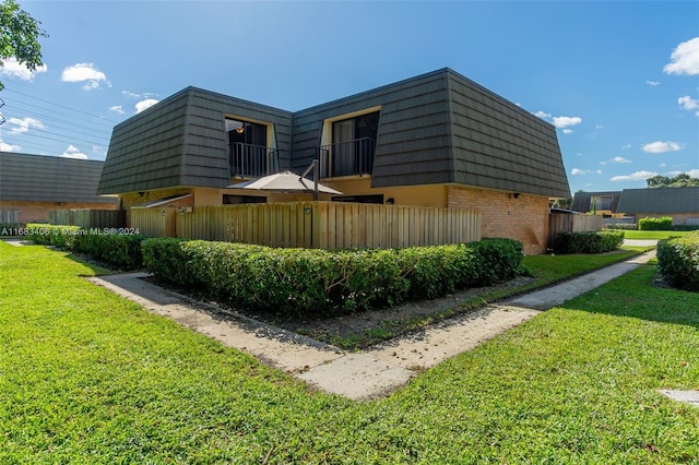 view of side of home featuring a lawn and a balcony