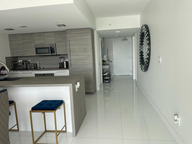 kitchen featuring a kitchen breakfast bar, sink, and light tile patterned floors