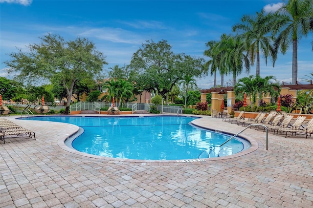 community pool with a patio and fence