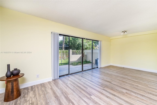 unfurnished room with a textured ceiling and light wood-type flooring