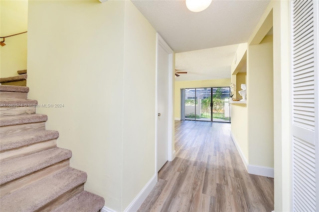 corridor with light hardwood / wood-style flooring and a textured ceiling