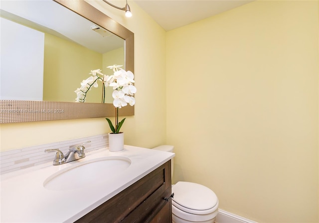 bathroom featuring vanity, decorative backsplash, and toilet