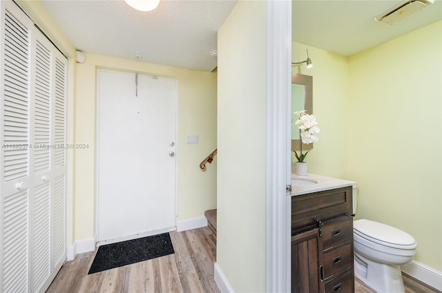 bathroom featuring vanity, a textured ceiling, hardwood / wood-style flooring, and toilet