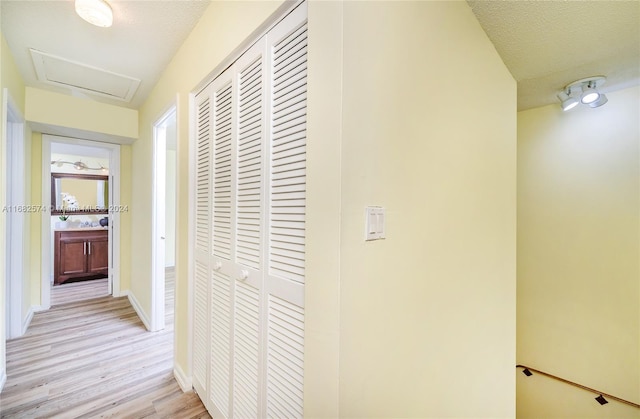 hall with a textured ceiling and light wood-type flooring