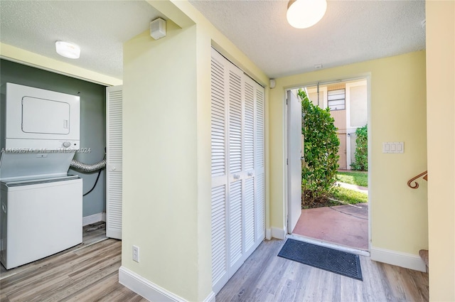 interior space with light hardwood / wood-style floors, a textured ceiling, and stacked washer / drying machine