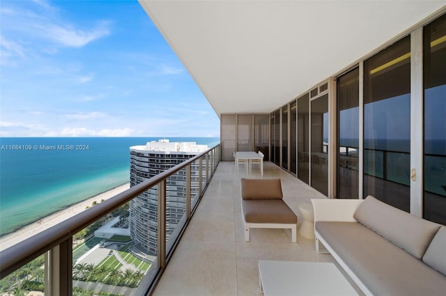 balcony with outdoor lounge area, a water view, and a view of the beach