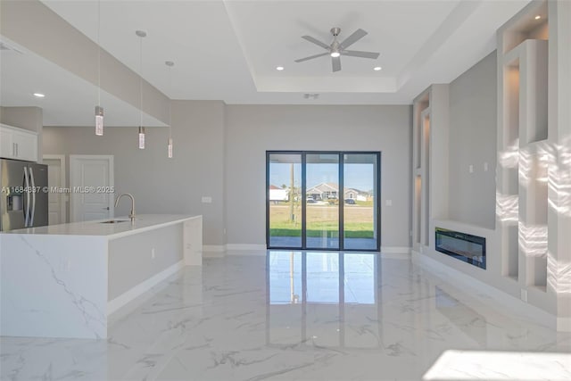 living room featuring ceiling fan, sink, and a tray ceiling