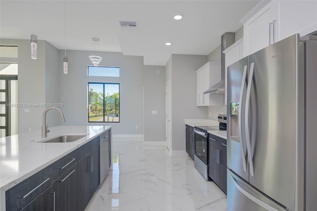 kitchen with stainless steel appliances, wall chimney range hood, sink, pendant lighting, and white cabinetry