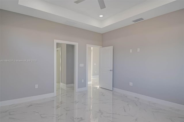 spare room with ceiling fan and a tray ceiling