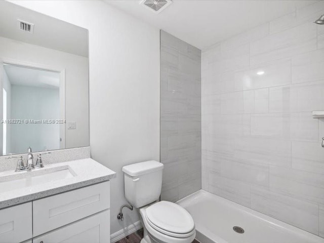 bathroom featuring toilet, vanity, and tiled shower