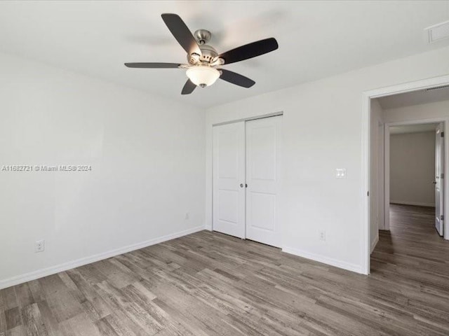 unfurnished bedroom with a closet, hardwood / wood-style flooring, and ceiling fan