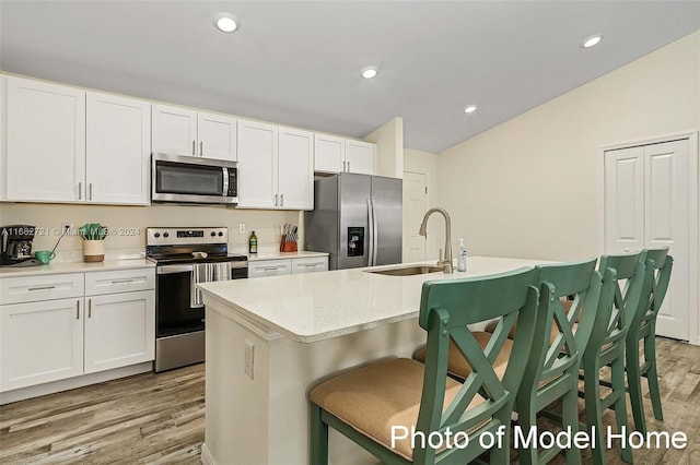 kitchen featuring stainless steel appliances, sink, light wood-type flooring, and a center island with sink