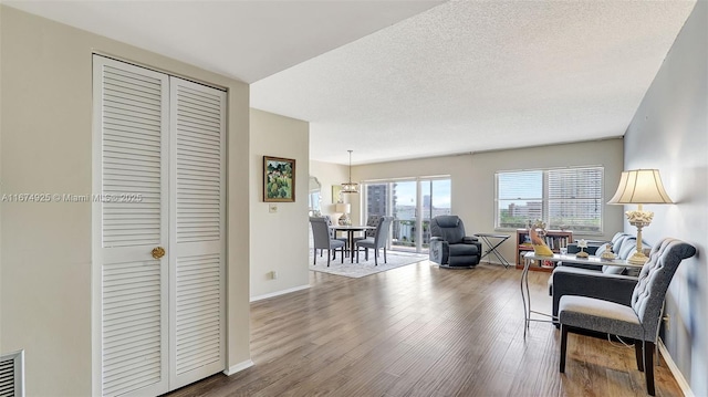 living room with a textured ceiling, wood finished floors, and baseboards